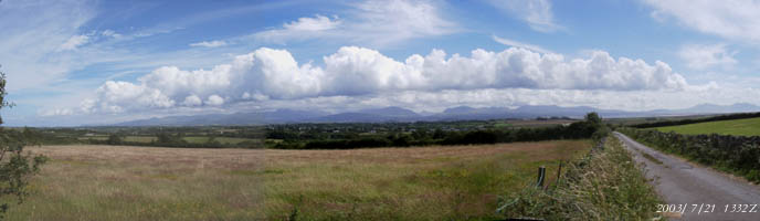 Linear cumulus cloud formation over Snowdonia. Centre view is looking S from Llangeinwen (SW Anglesey) over the village of Dwyran towards Caernarfon and Yr Wyddfa (Snowdon) above. On the left are the Carneddau and on the right the water in Caernarfon Bay and mountains of the Lleyn Peninsula. 