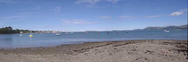 Beaumaris and the Menai Strait looking NE from Gallows Point on a sunny afternoon on 5 July 2004. Click to see larger image. 