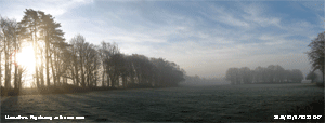 Sun rising and early fog clearing over frost covered field. 