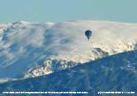 Hot air balloon traverses the mountain snow.