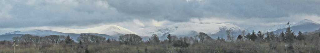 Cumulus clouds over moderate snow on the Carneddau Mountains.